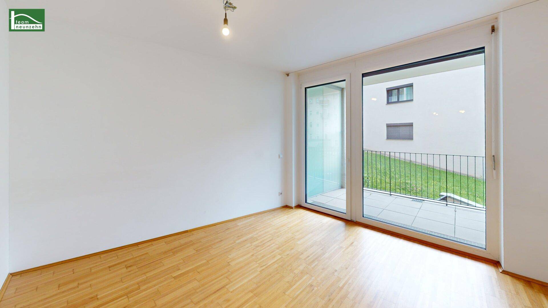 Heller Wohnraum mit Holzboden und Zugang zu einer Terrasse mit Blick ins Grüne.