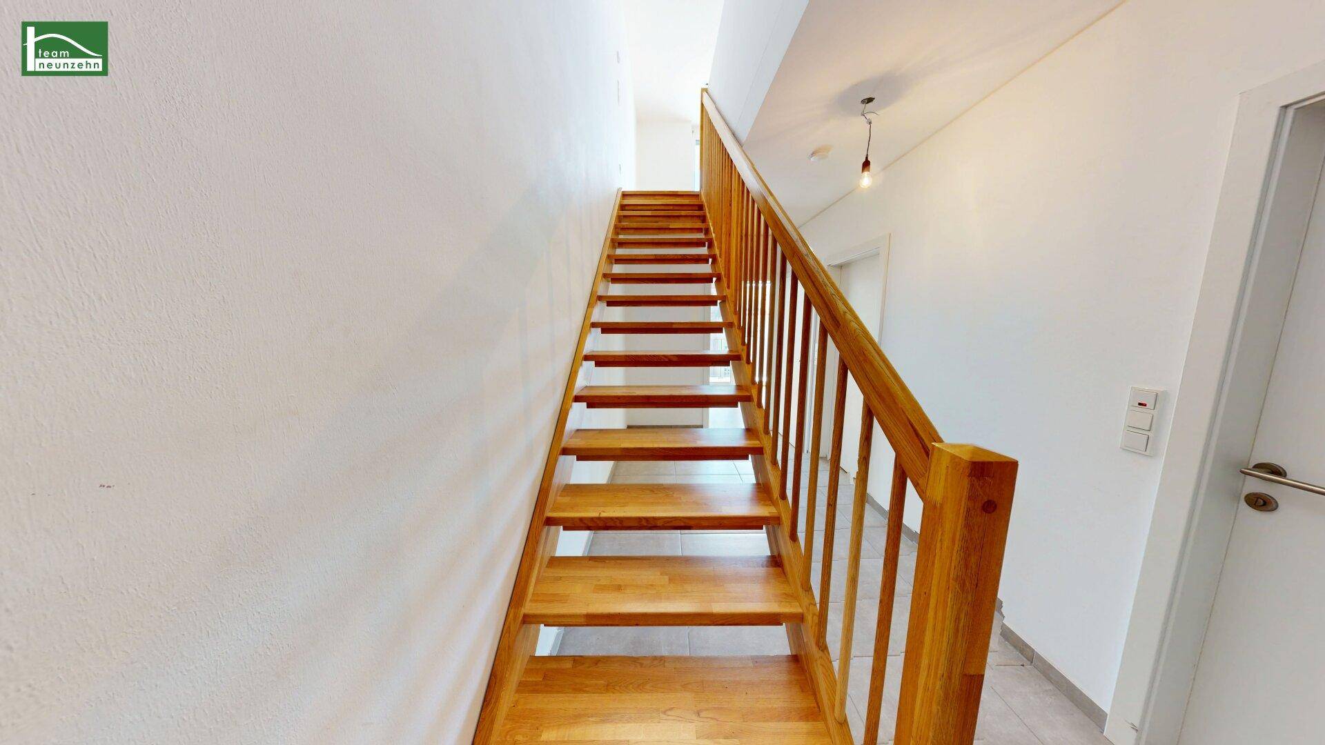 Helle Holztreppe mit Geländer, die in die obere Etage des Hauses führt.