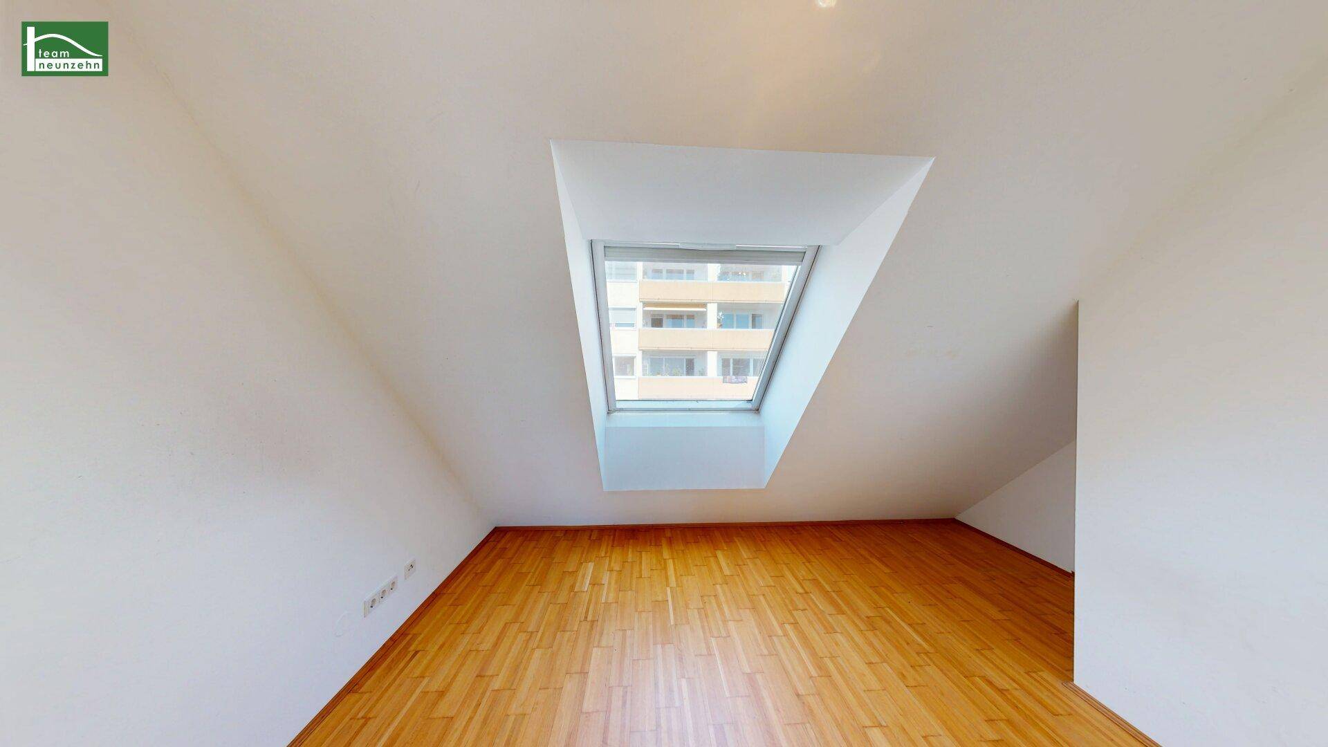 Dachgeschosszimmer mit Holzboden und Dachfenster, das viel natürliches Licht hereinlässt.