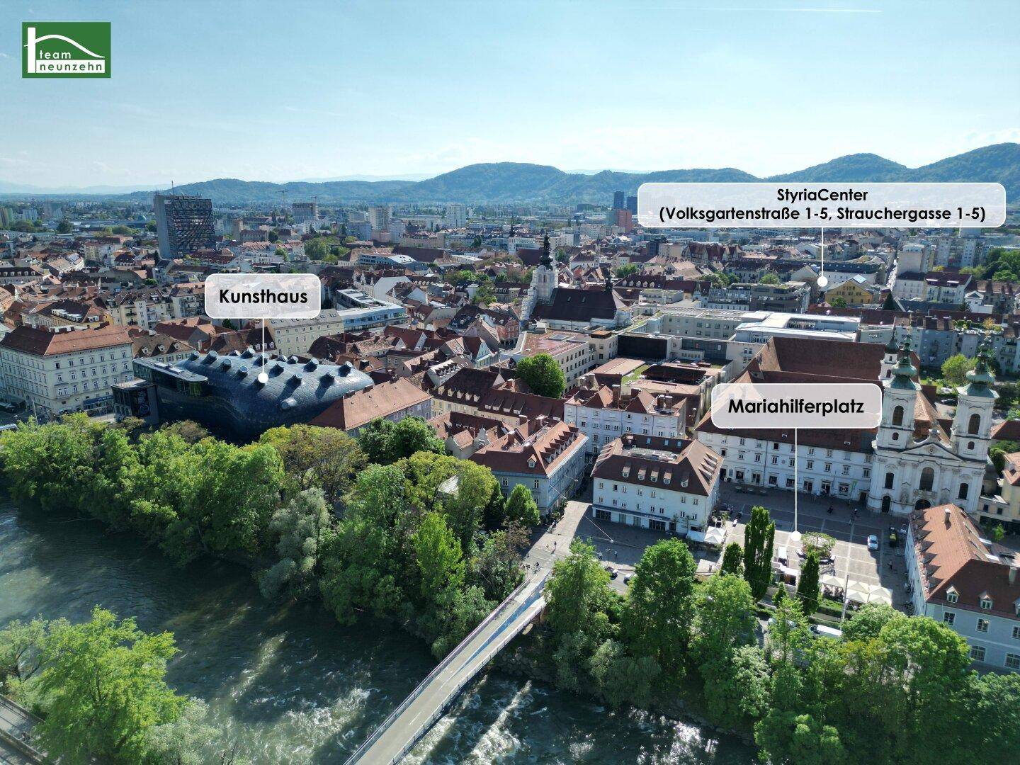 Luftaufnahme der Stadt mit Fluss, historischen Gebäuden und Bergen im Hintergrund, inklusive markierter Sehenswürdigkeiten.