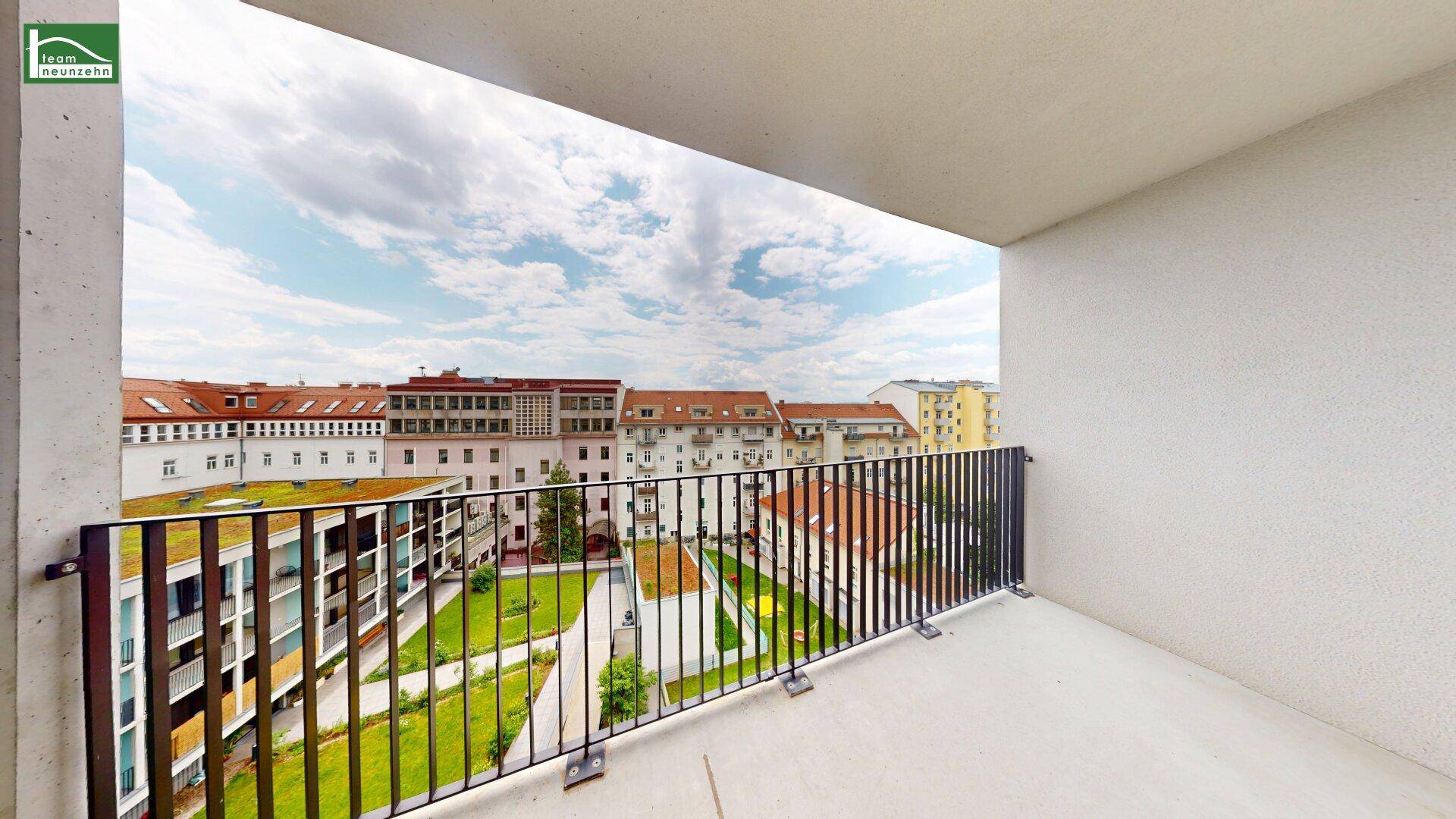 Geräumiger Balkon mit Blick auf einen begrünten Innenhof und die umliegenden Gebäude.