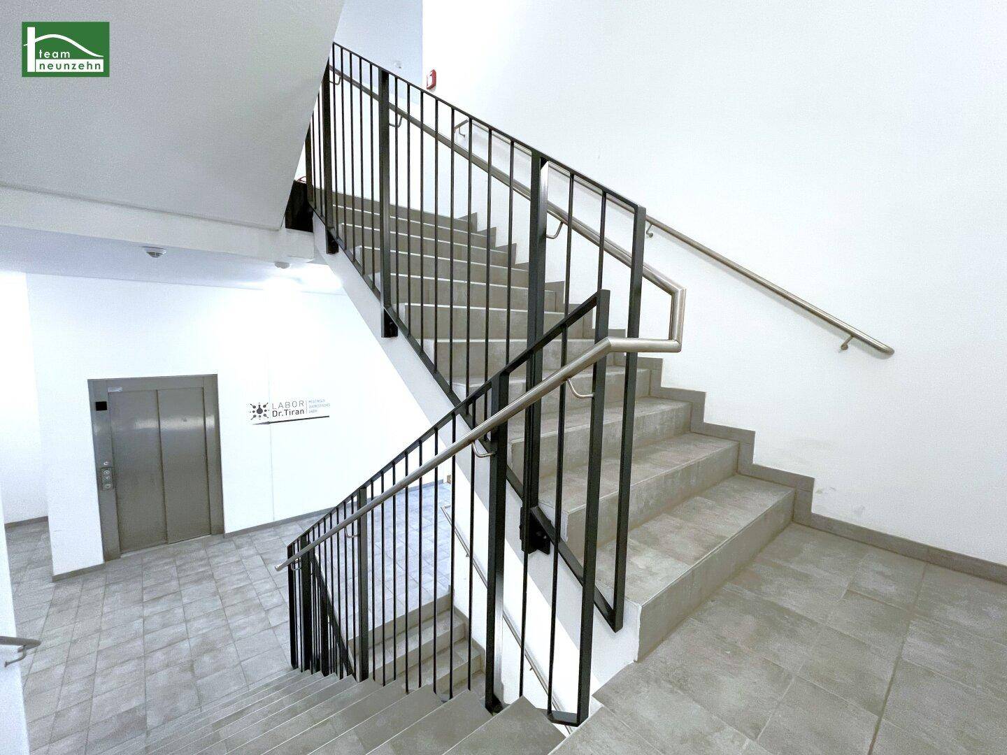 Modernes Treppenhaus mit Metallgeländer und Aufzug in einem Mehrfamilienhaus.