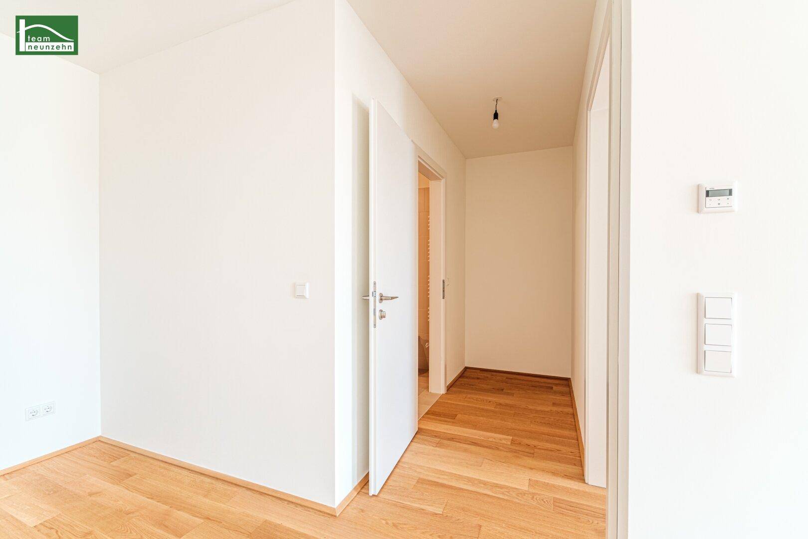 Heller Flur mit Holzboden und weißen Türen, der verschiedene Räume miteinander verbindet.