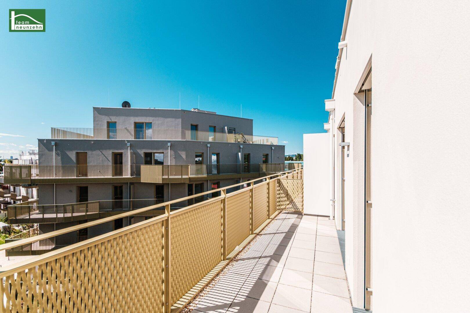 Geräumiger Balkon mit modernen Metallgeländern und Blick auf die umliegenden Neubauten.