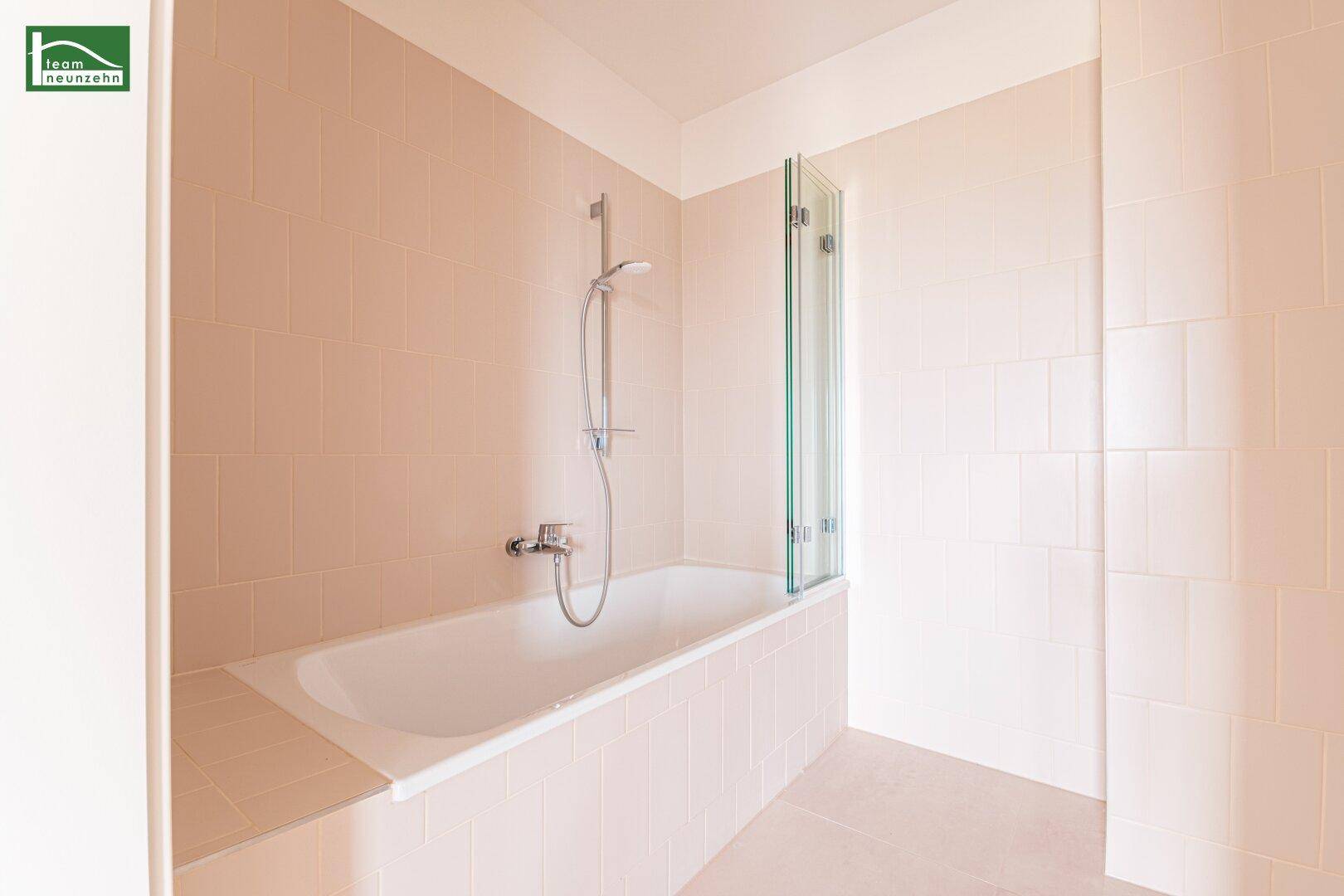 Modernes Badezimmer mit Badewanne, Duschabtrennung und hellen Fliesen.