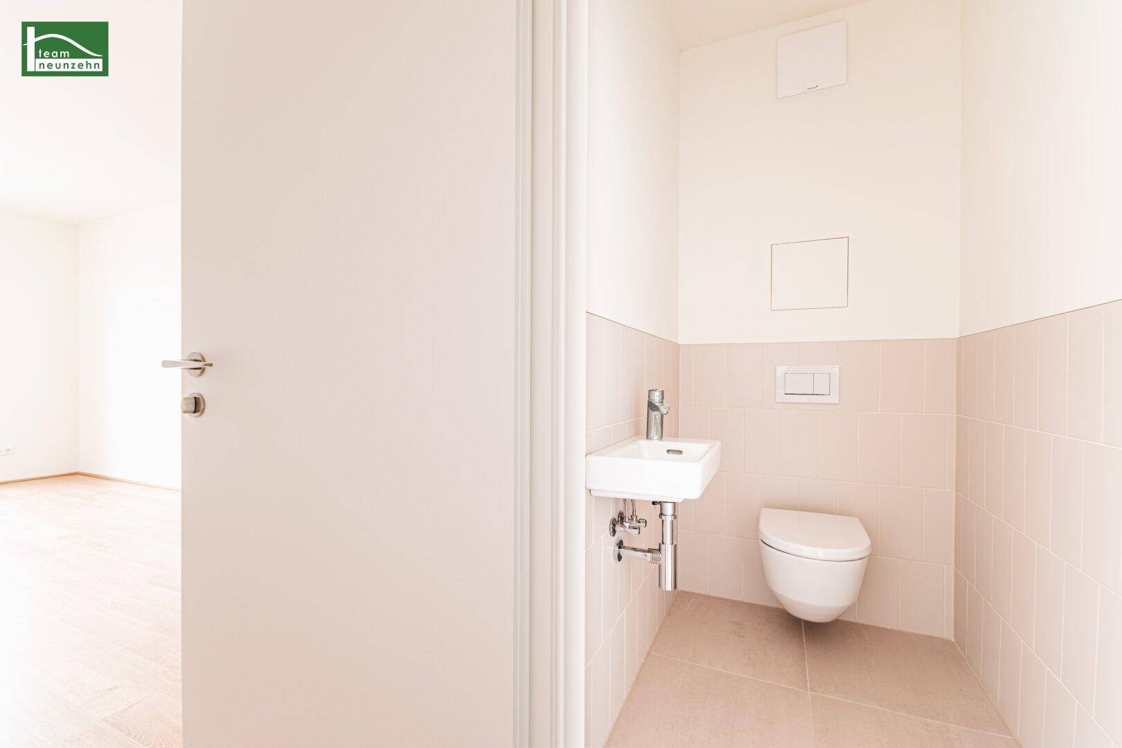 Separates Gäste-WC mit wandhängender Toilette und kleinem Waschbecken.