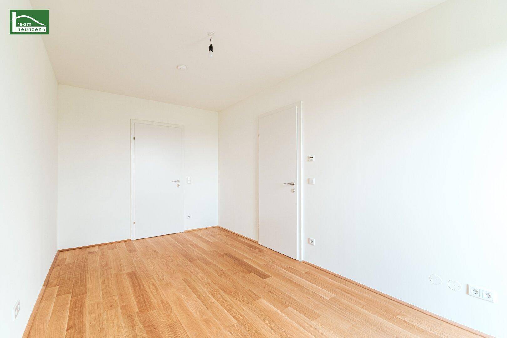 Unmöbliertes Zimmer mit Holzboden und weißen Wänden, bereit zum Einzug.