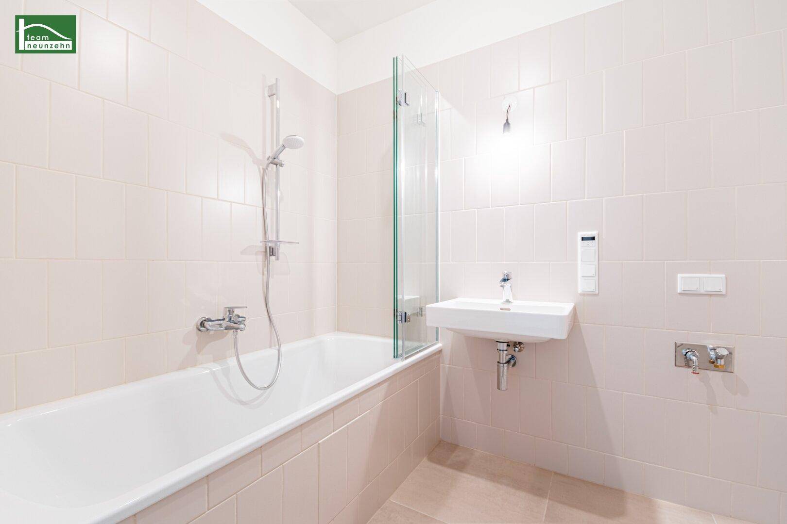 Helles Badezimmer mit Badewanne, Duschabtrennung und modernem Waschbecken.