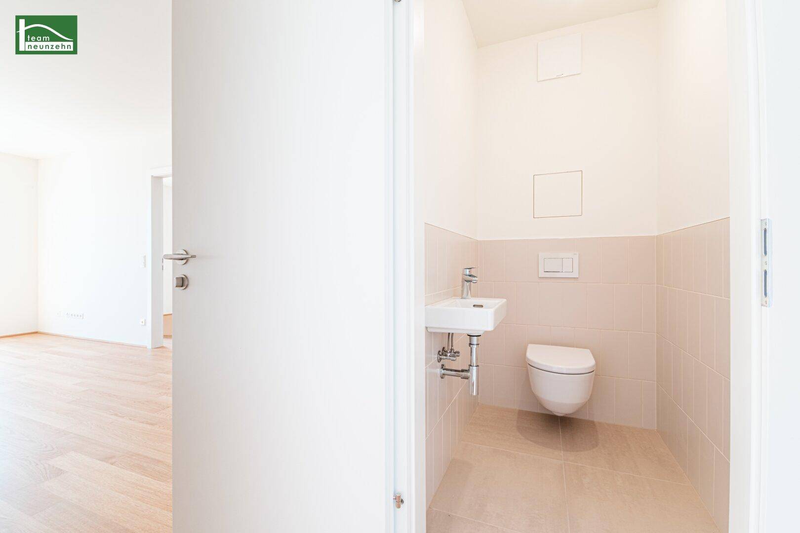 Kleines Gäste-WC mit wandhängendem WC und kompaktem Waschbecken, in hellen Tönen gehalten.