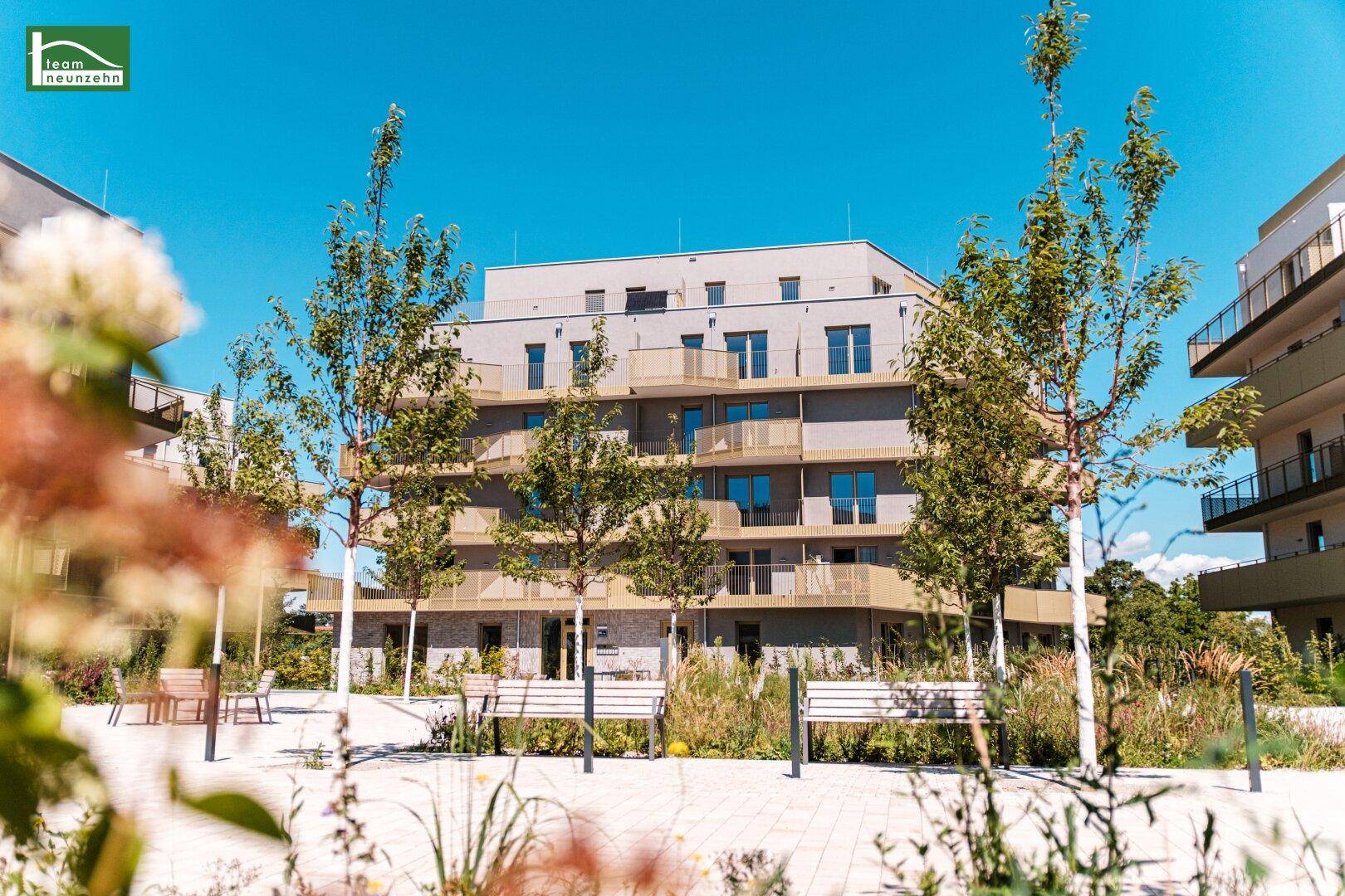 Moderne Wohnanlage mit ansprechender Architektur und begrünten Außenbereichen unter blauem Himmel.
