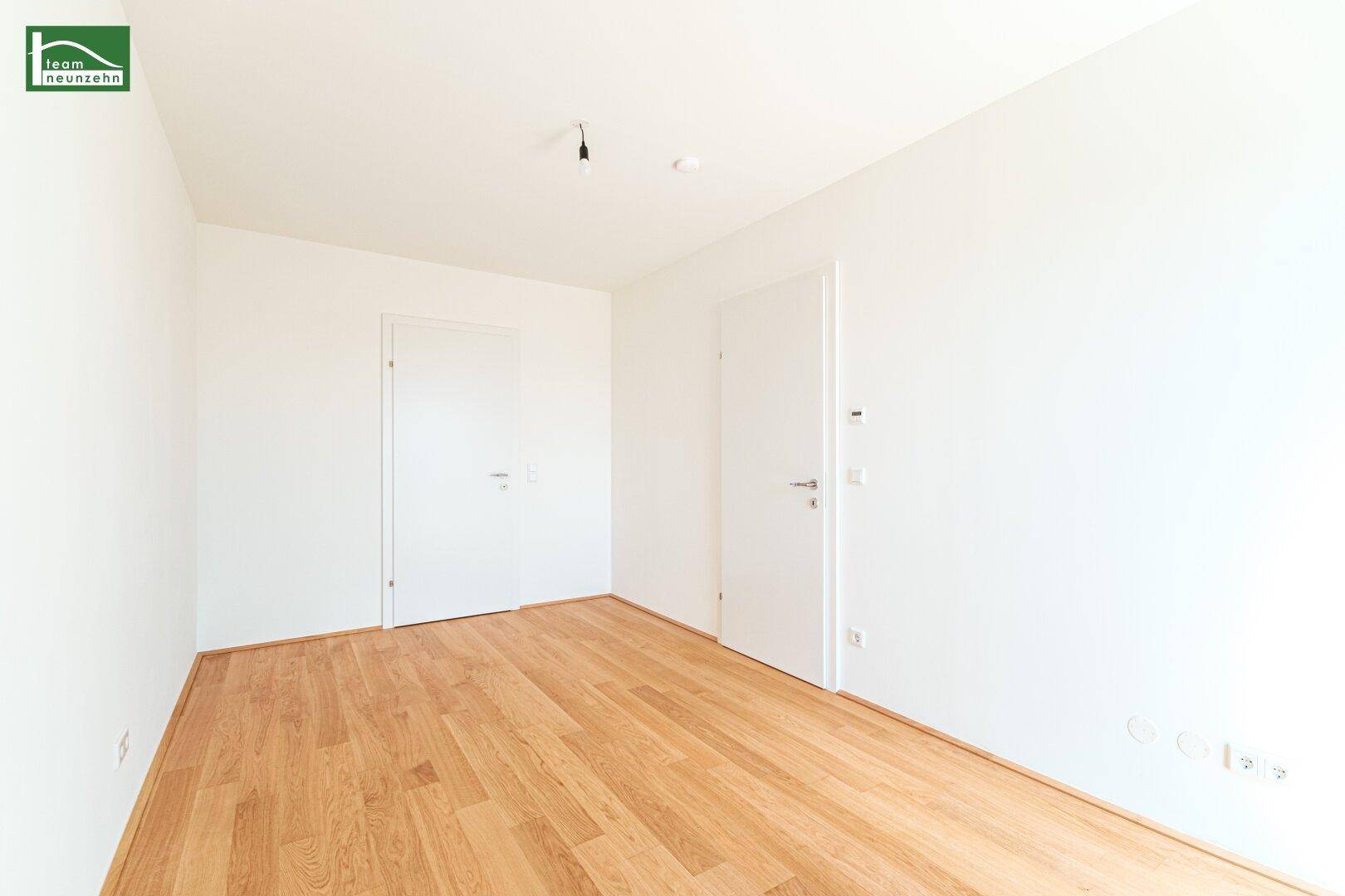 Leeres Zimmer mit Holzboden und weißen Wänden, ideal als Schlafzimmer oder Büro nutzbar.