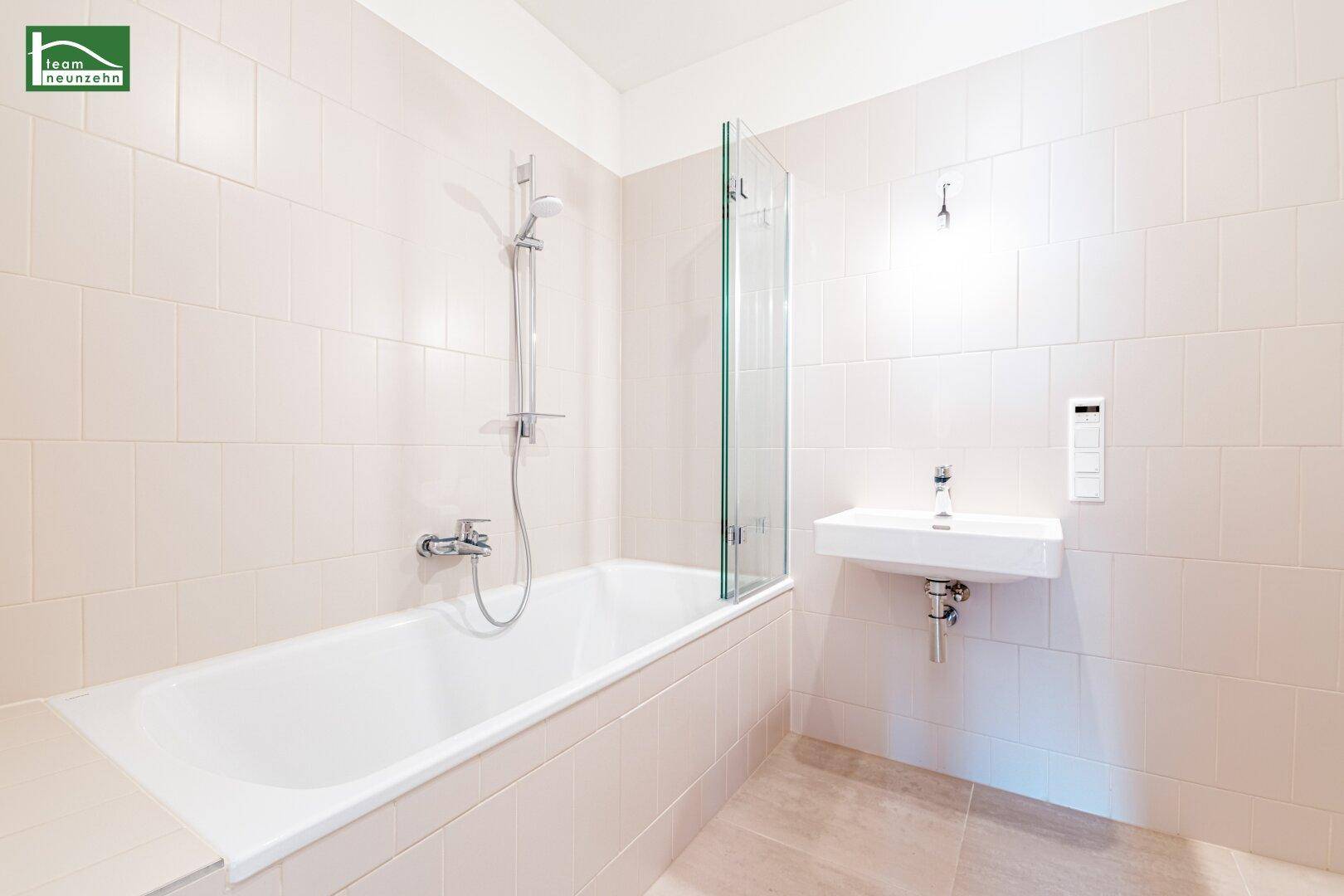 Modernes Badezimmer mit Badewanne, Duschabtrennung und einem kleinen Waschbecken.