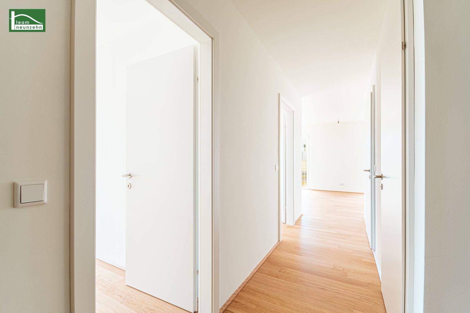 Heller Flur mit Holzboden und mehreren weißen Türen, der zu verschiedenen Räumen führt.