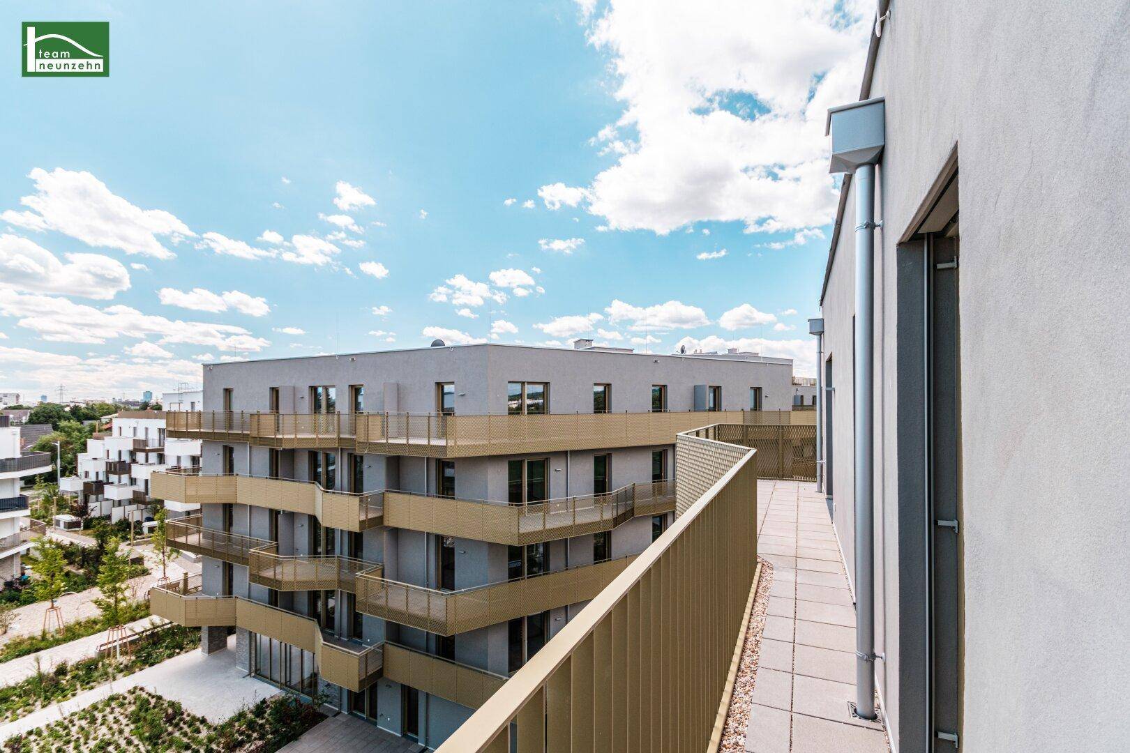 Langer Balkon mit moderner goldener Brüstung und Blick auf die umliegenden Gebäude.