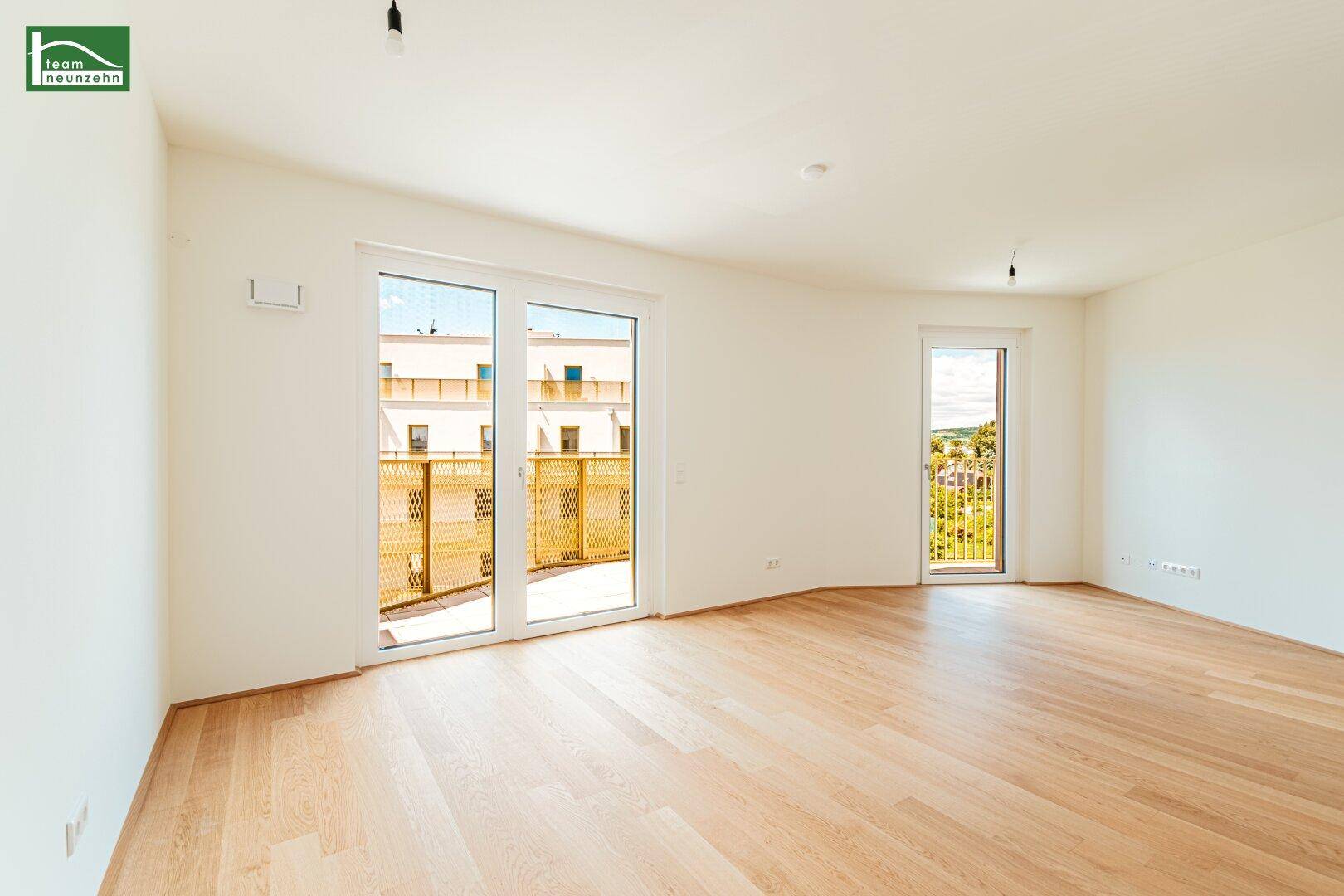 Heller Wohnraum mit Holzboden und Zugang zu einem Balkon, bietet viel natürliches Licht.