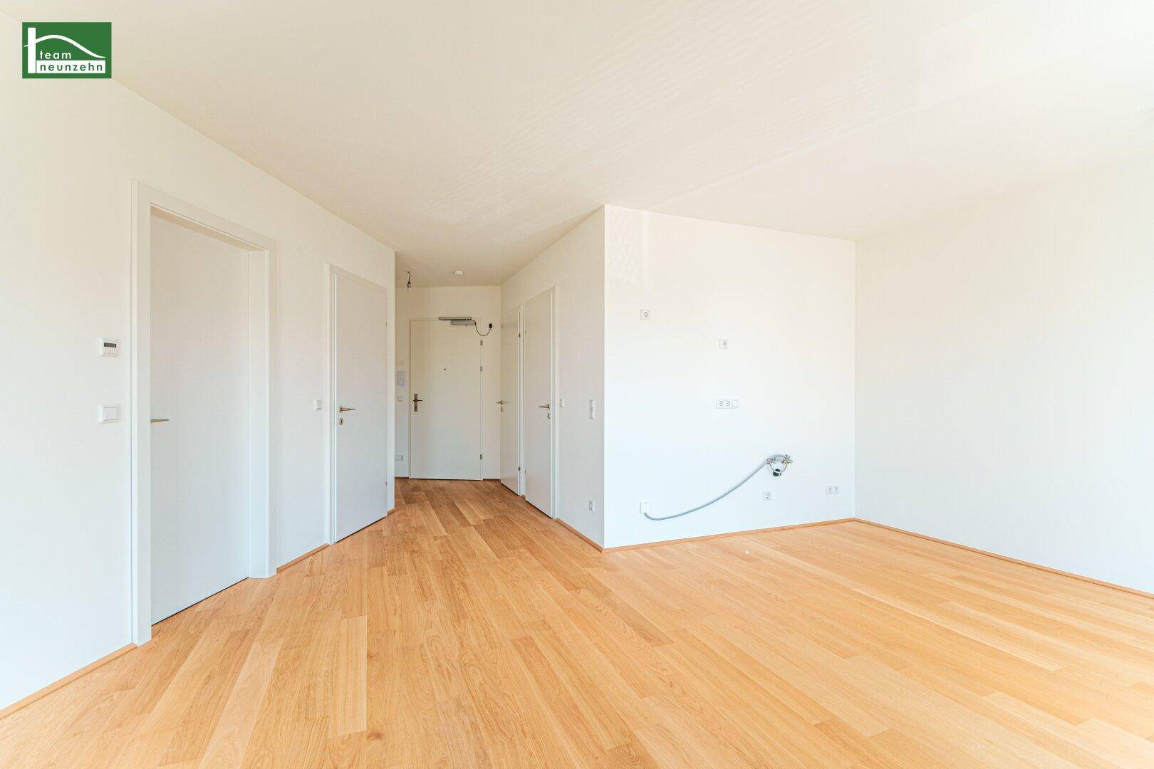Geräumiger Flur mit hellem Holzboden und mehreren Türen zu den angrenzenden Räumen.