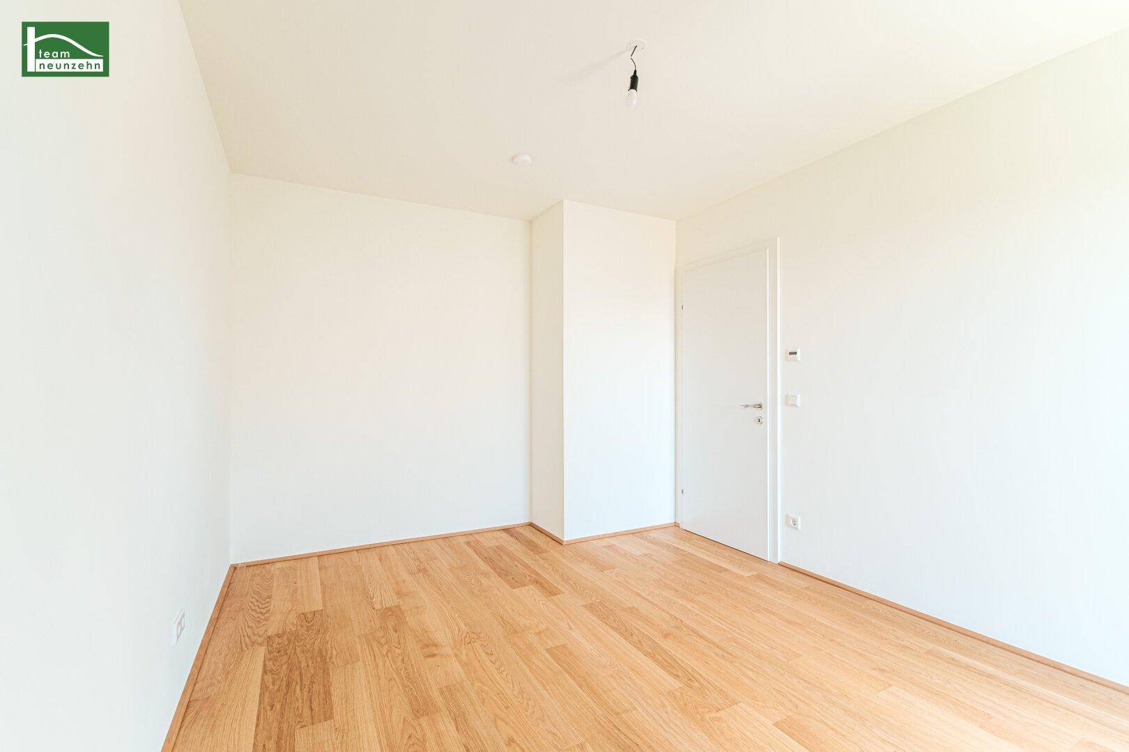 Leeres Zimmer mit hellem Holzboden und weiß gestrichenen Wänden, bereit zum Einrichten.