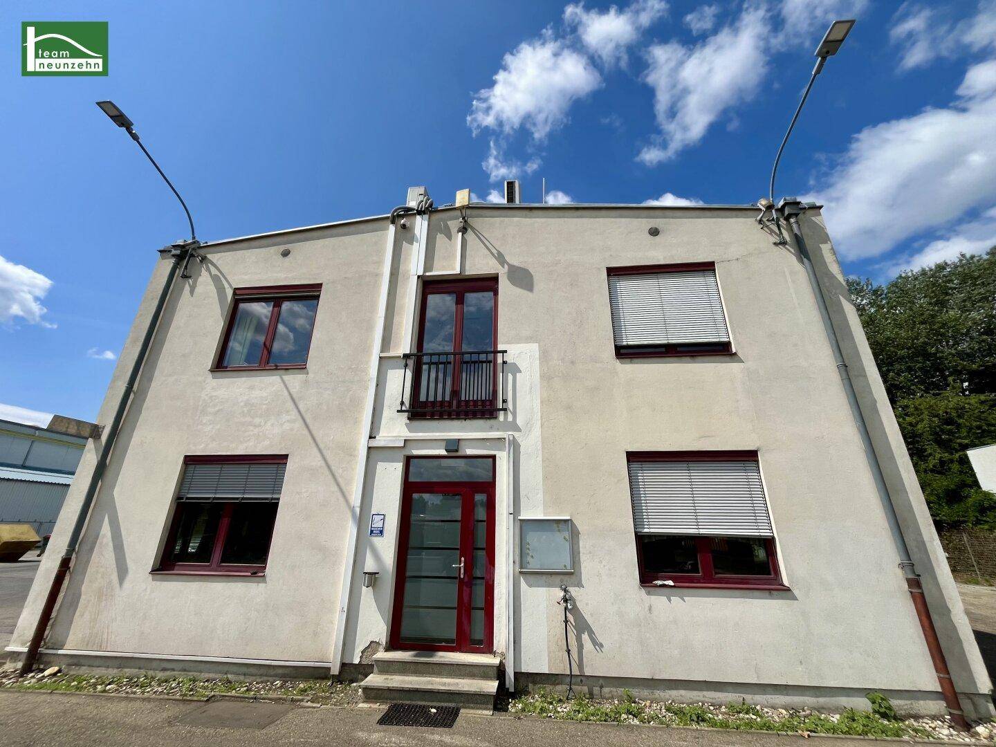 Vorderansicht des Gebäudes mit Eingangstür, Fenstern und einem kleinen Balkon.