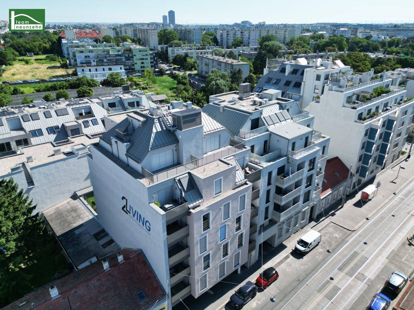 Luftaufnahme eines modernen Wohngebäudes in städtischer Umgebung mit umliegenden Gebäuden und Straßen.