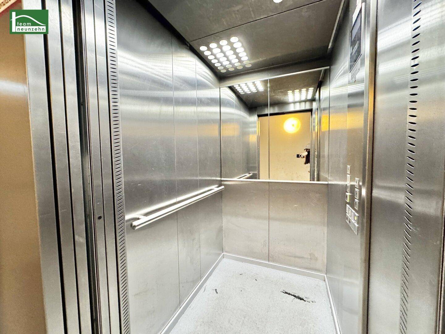 Moderner Aufzug mit Edelstahlverkleidung und Spiegel für bequemen Zugang.