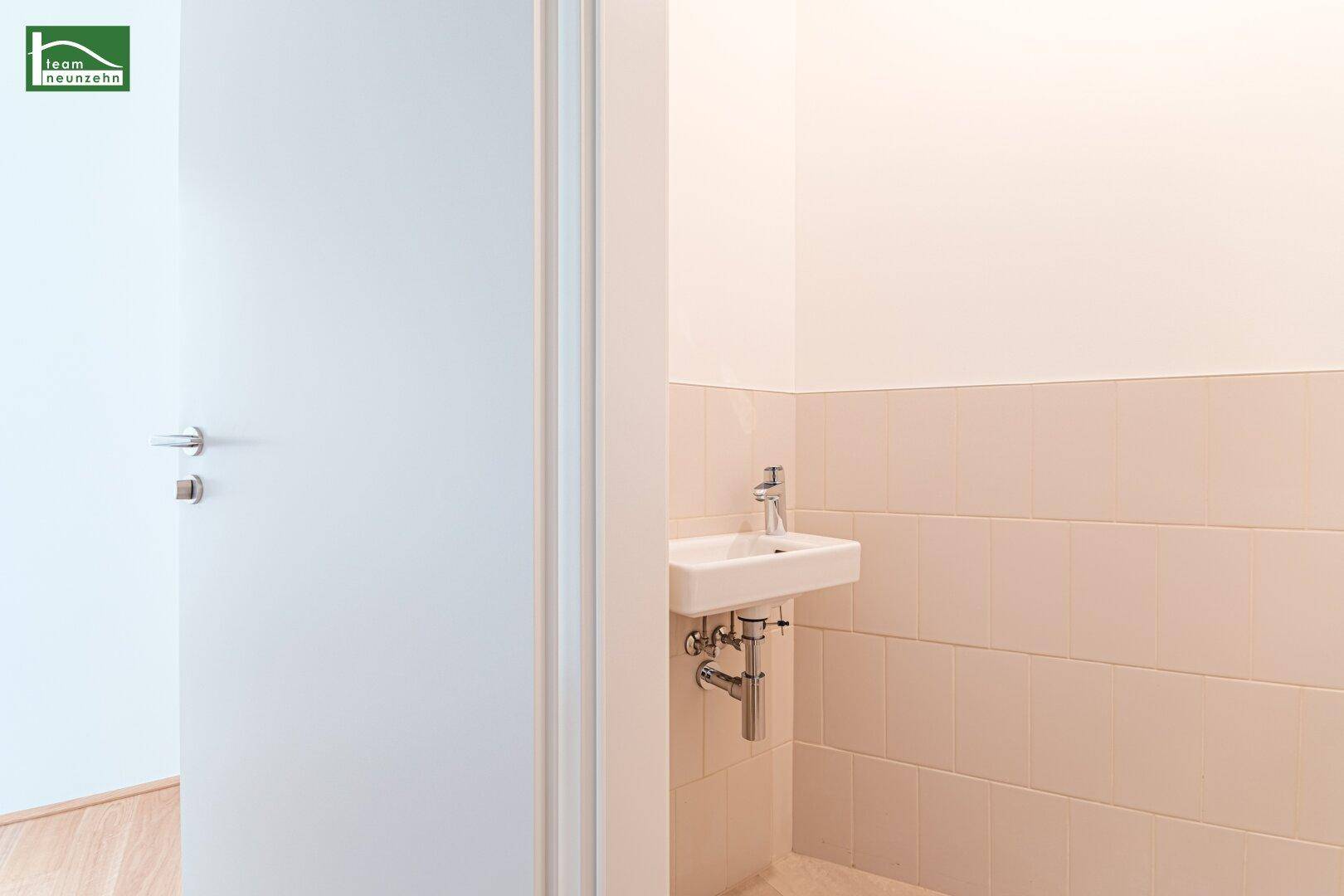 Kleiner Waschbereich mit Einzelwaschbecken und hellen Fliesen, ideal für ein Gäste-WC.