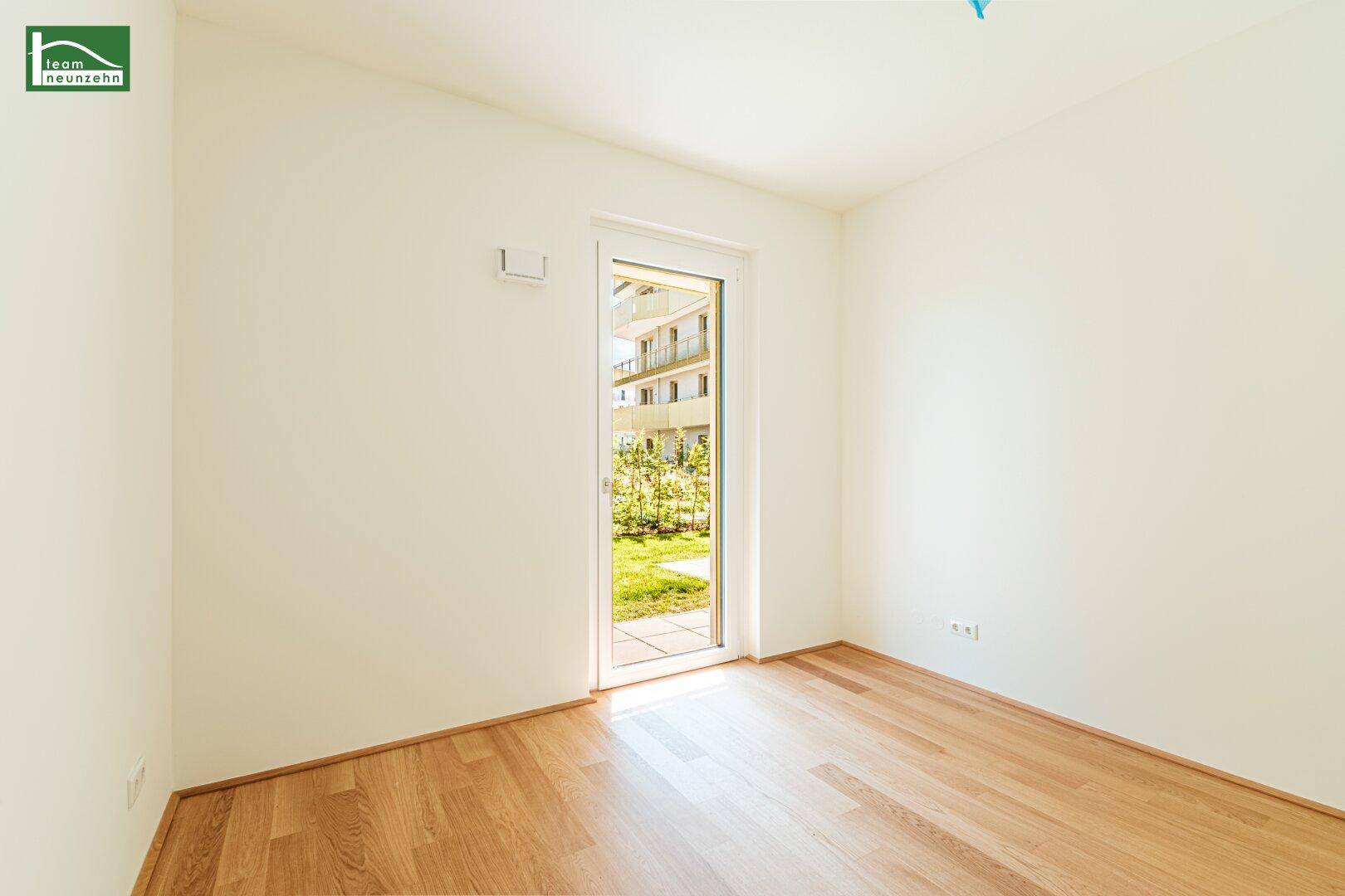 Helles Schlafzimmer mit Parkettboden und direktem Zugang zu einem Außenbereich.