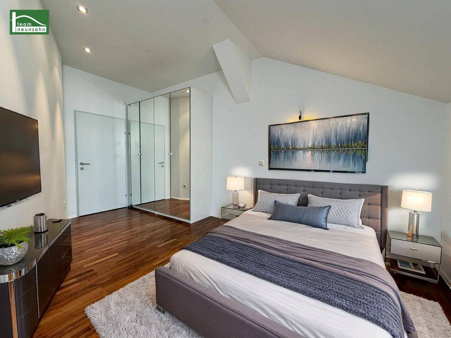 Gemütliches Schlafzimmer mit Doppelbett, dunklem Parkett und integriertem Spiegelschrank.
