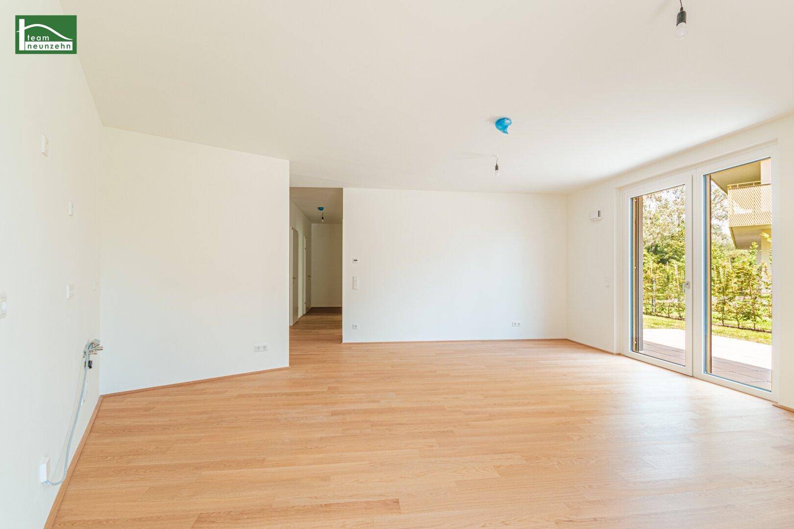 Geräumiges, helles Wohnzimmer mit Parkettboden und großen Schiebetüren zum Außenbereich.