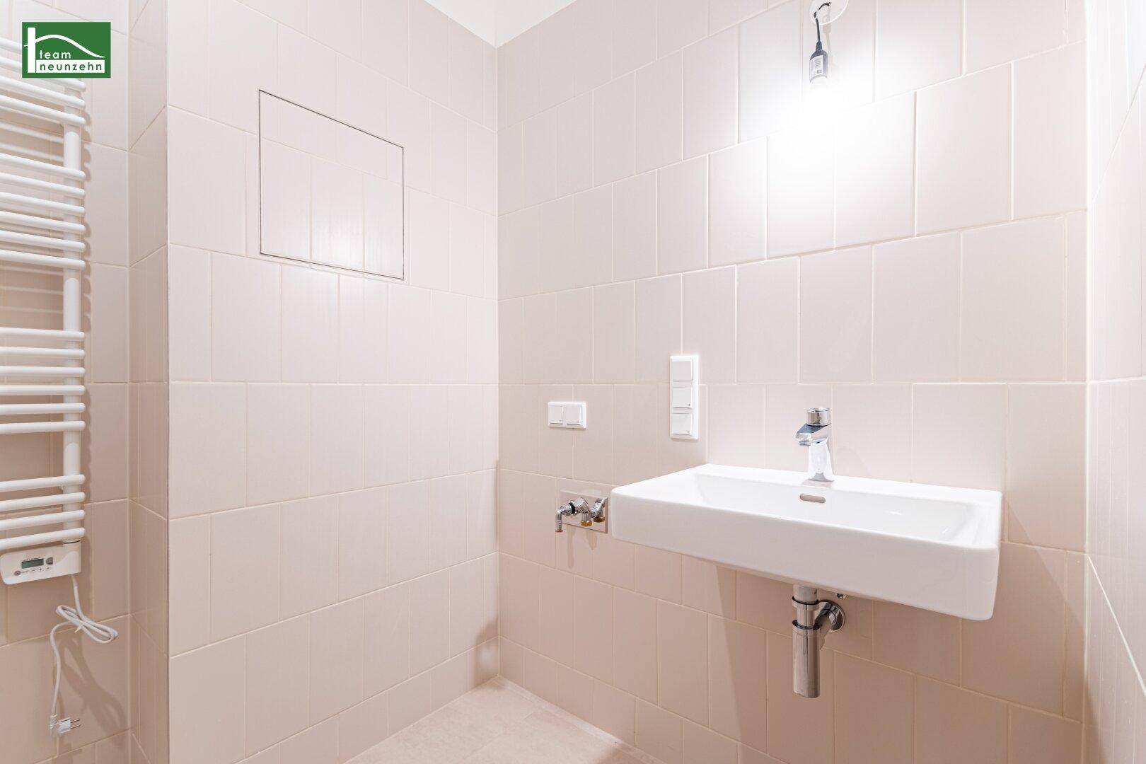 Badezimmer mit modernem Einzelwaschbecken und praktischem beheiztem Handtuchhalter.