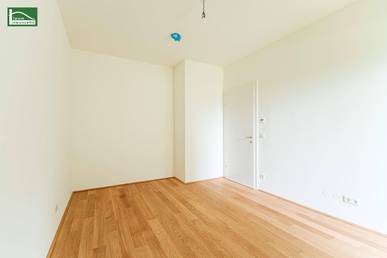 Leeres Zimmer mit hellem Holzboden und weißen Wänden, bereit zur individuellen Gestaltung.