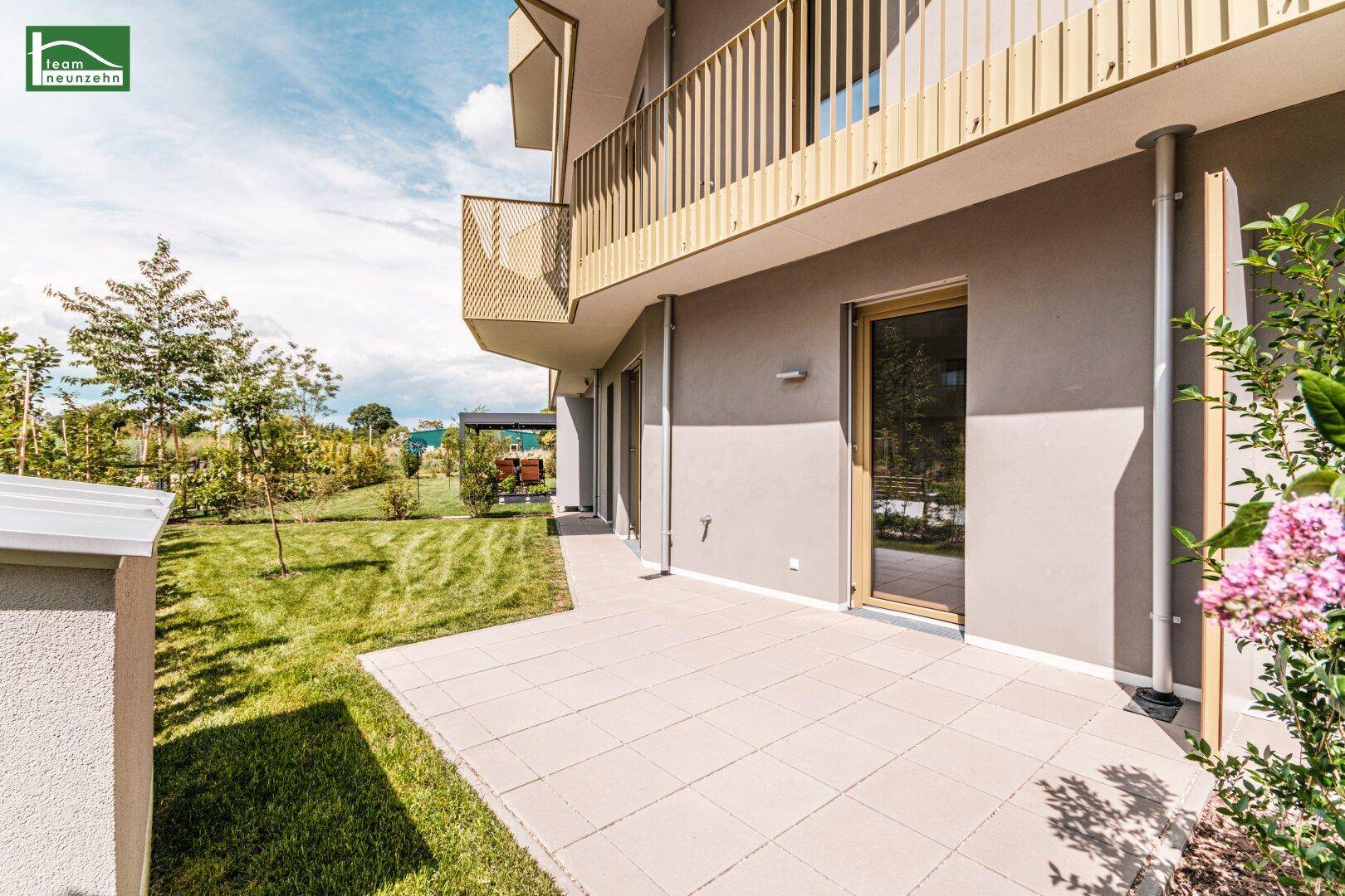 Geräumige Terrasse mit Steinplatten und direktem Zugang zum Garten, umgeben von Grün.
