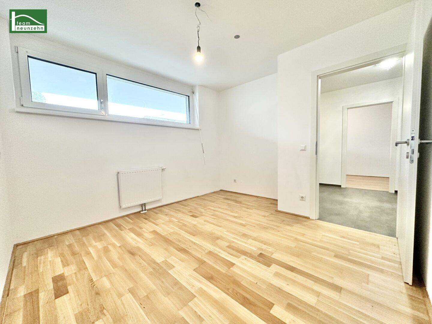 Helles Schlafzimmer mit Parkettboden und großen Fenstern, bereit zur individuellen Gestaltung.