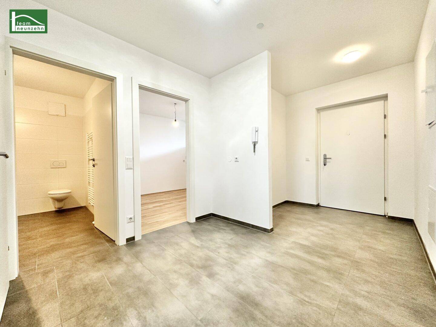 Heller Flur mit Fliesenboden, der Zugang zu den verschiedenen Räumen bietet.