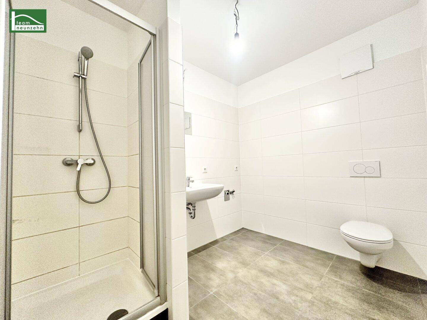 Modernes Badezimmer mit Dusche, WC und Waschbecken, hell gefliest.