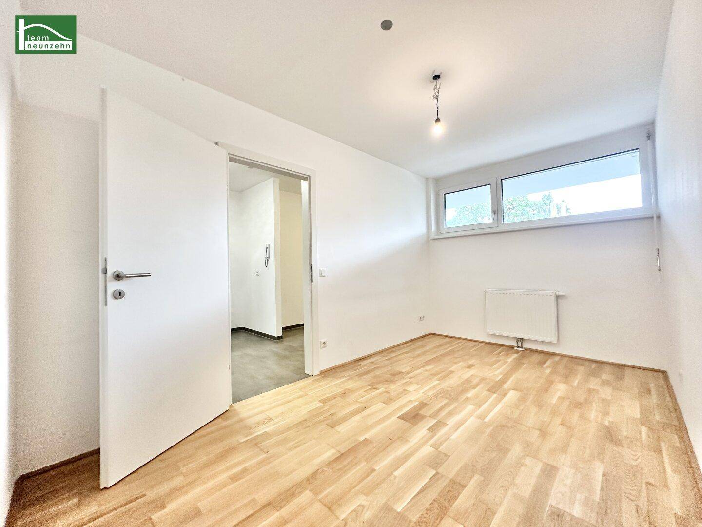 Geräumiges Zimmer mit Parkettboden und großen Fenstern, ideal als Schlaf- oder Arbeitszimmer.