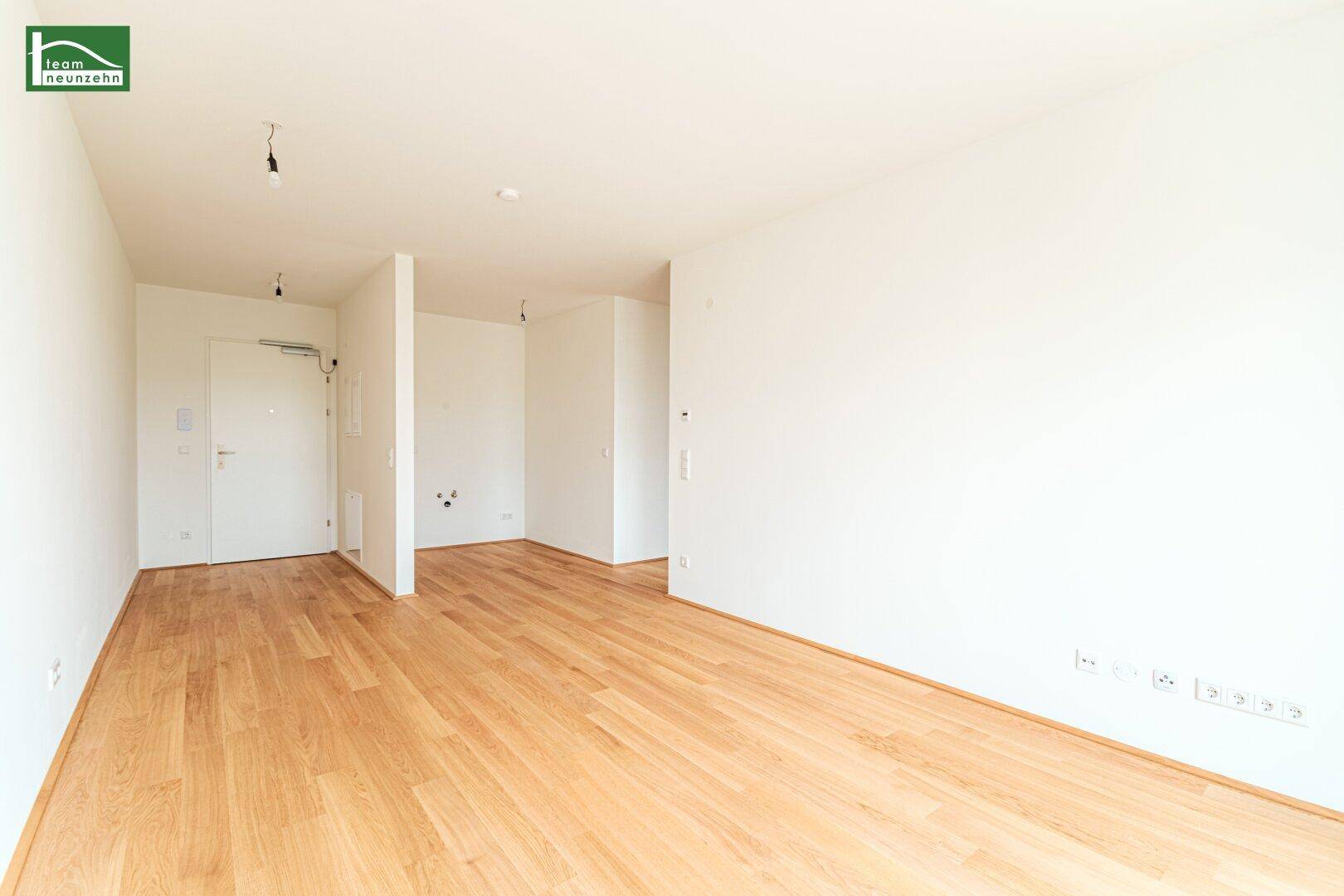 Helles, leeres Zimmer mit Parkettboden und weiß gestrichenen Wänden, bereit zur Einrichtung.