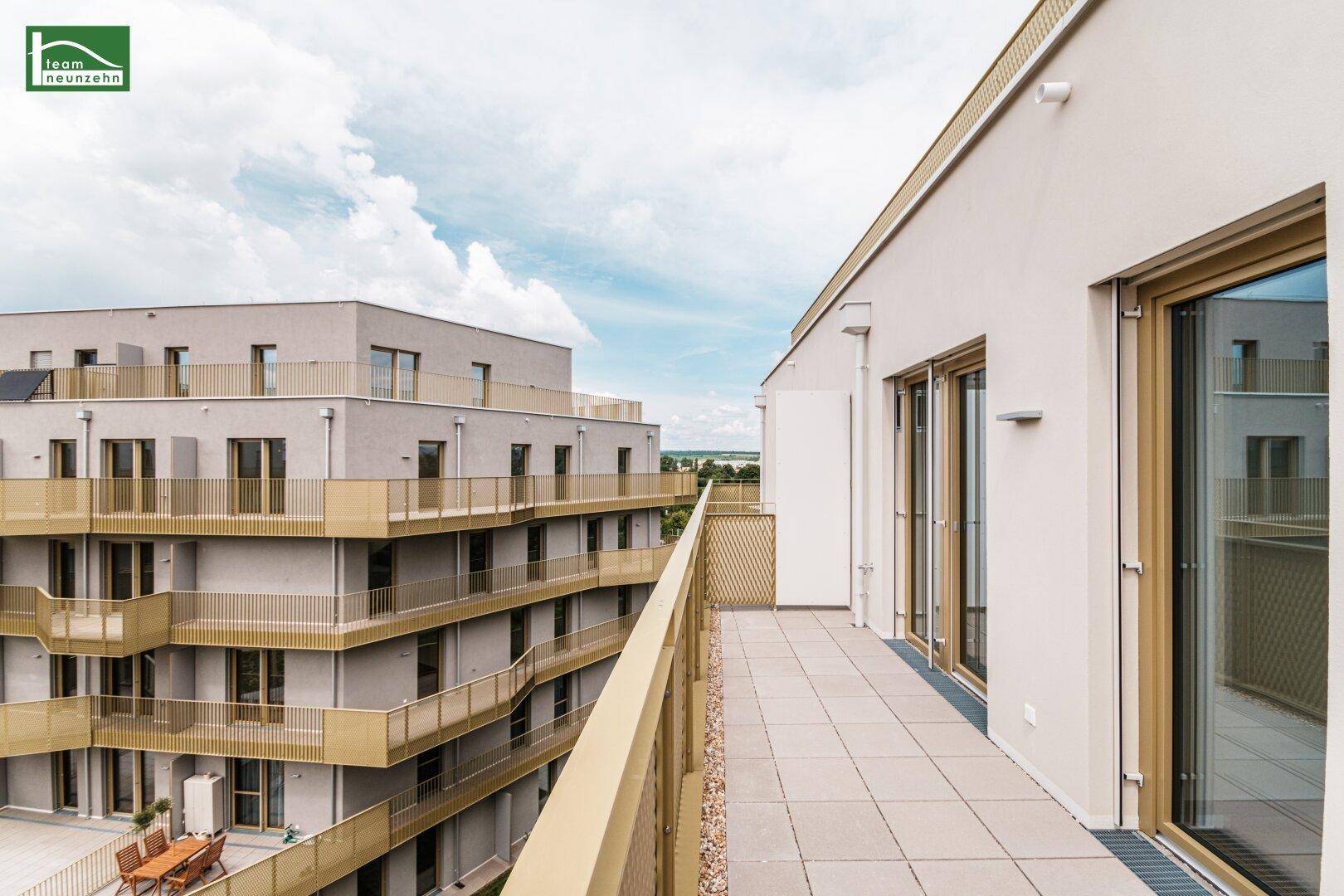 Geräumiger Balkon mit Fliesenboden und Blick auf moderne Wohngebäude in der Umgebung.