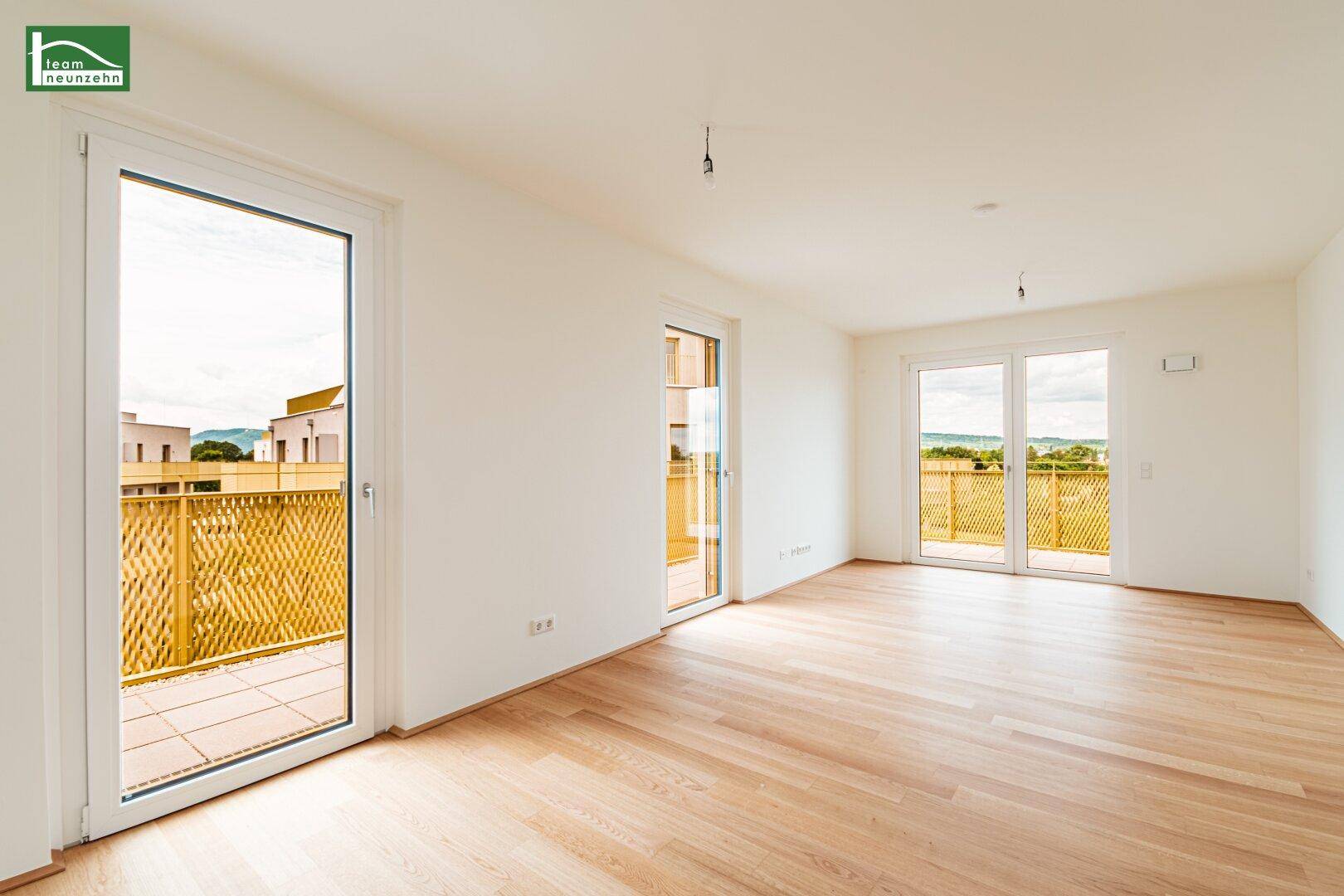 Lichtdurchfluteter Wohnbereich mit Parkettboden und mehreren Zugängen zu einem großen Balkon.
