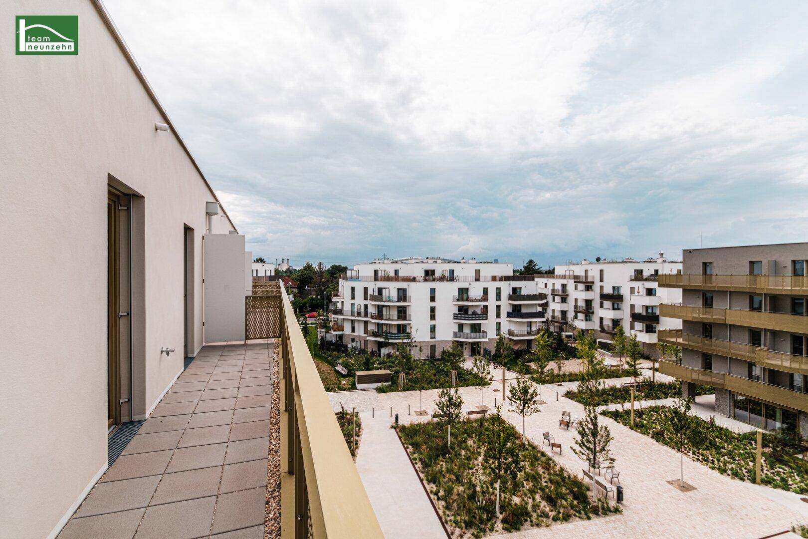 Geräumiger Balkon mit Fliesenboden und Blick auf die umliegenden modernen Wohngebäude.