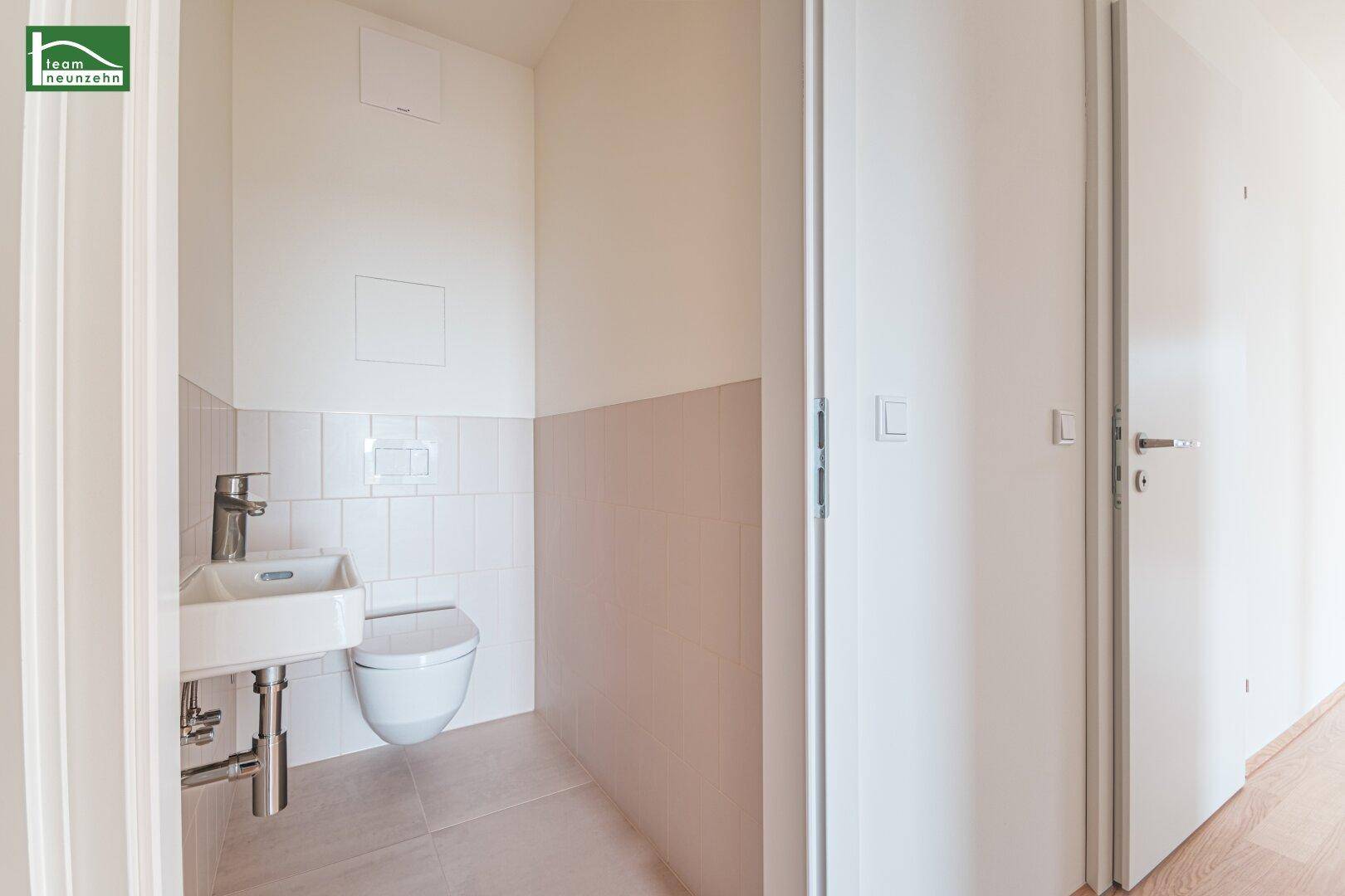 Funktionale Gästetoilette mit wandhängendem WC und kleinem Waschbecken in hellen Farbtönen.