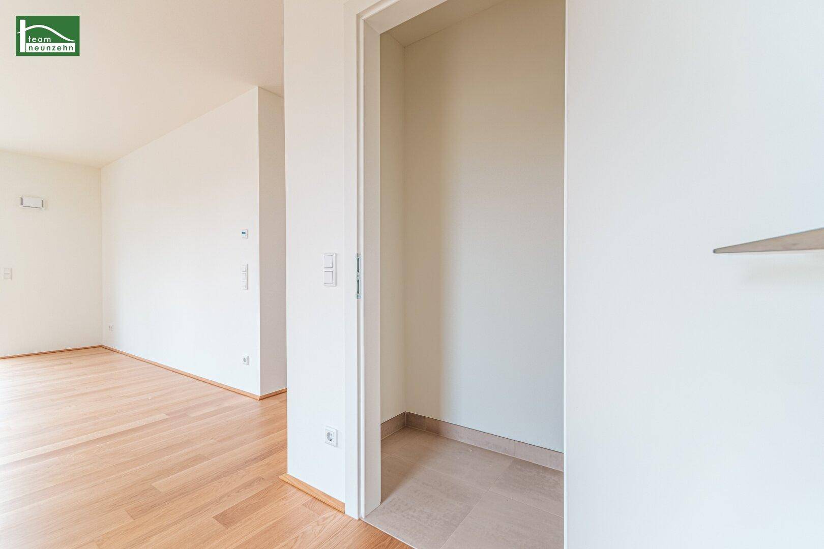 Heller Raum mit Parkettboden und einer Nische, die als Abstellraum oder Garderobe dienen könnte.