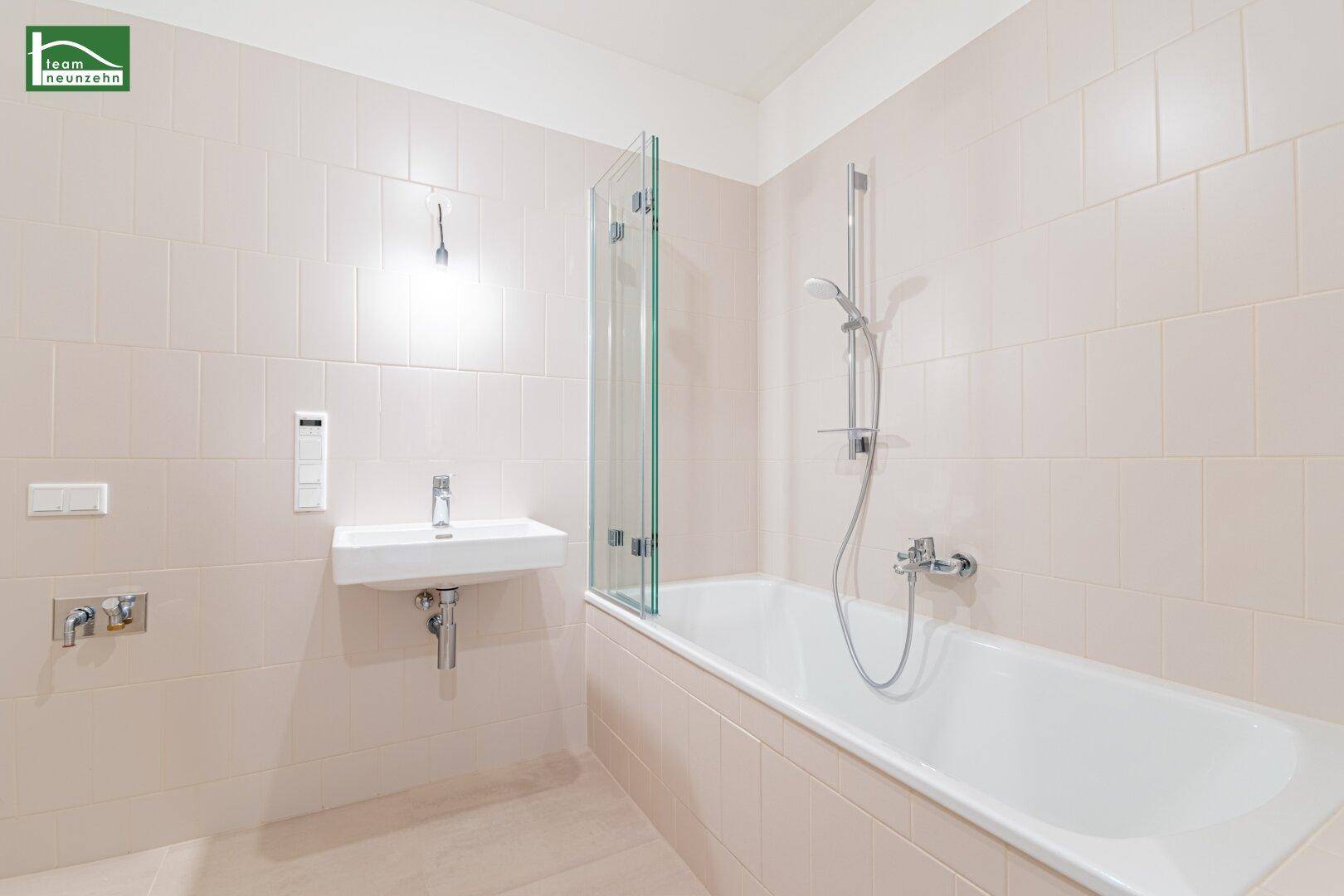 Modernes Badezimmer mit Badewanne, Duschabtrennung und hellem Fliesenboden.