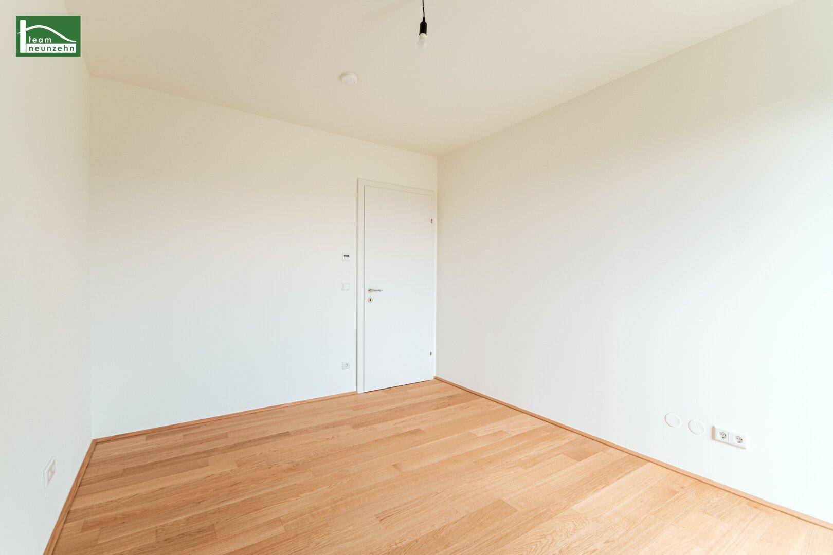 Leeres Zimmer mit Holzboden und weißen Wänden, bietet viel Potenzial für individuelle Einrichtung.