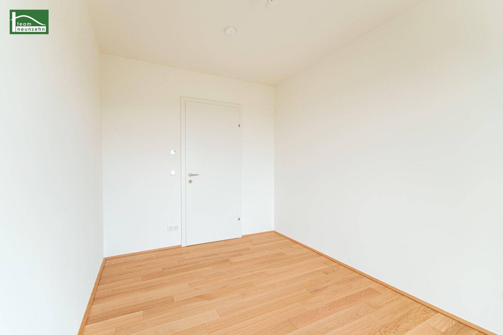 Unmöbliertes Zimmer mit weiß gestrichenen Wänden und Holzboden, bereit für neue Bewohner.