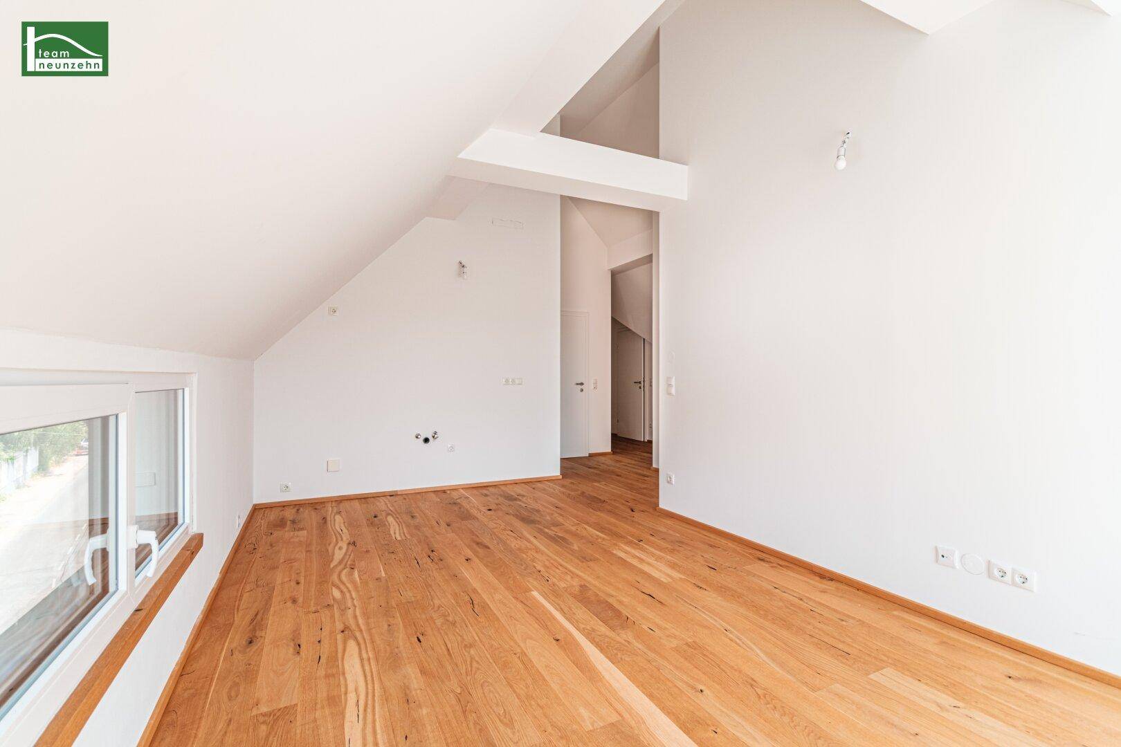 Heller Flur im Dachgeschoss mit Holzboden und Zugang zu weiteren Räumen.