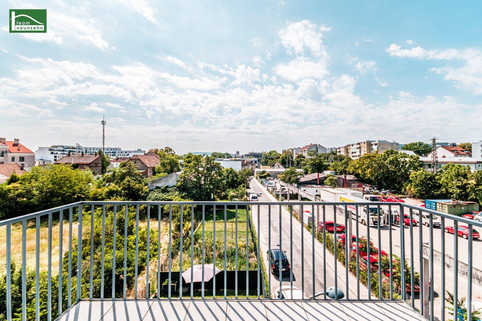 Geräumiger Balkon mit Fliesenboden und Blick auf die Straße und Grünflächen.