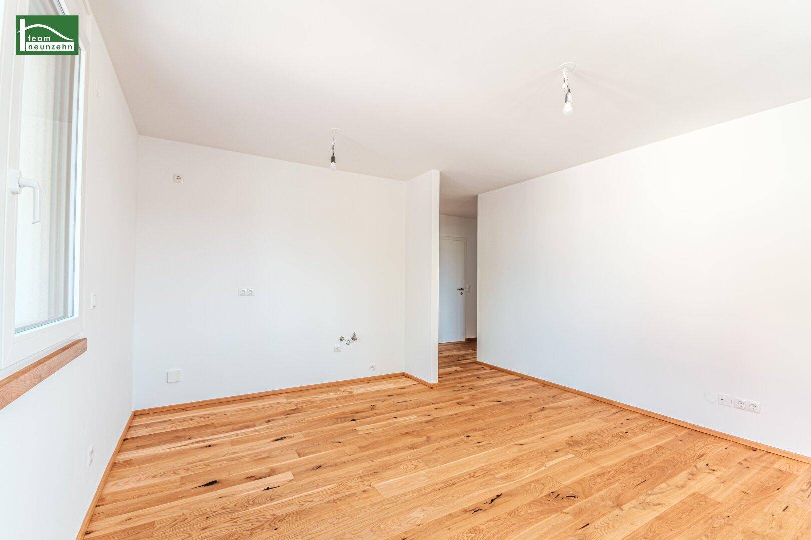 Leerer Raum mit hellem Holzboden und weißen Wänden, bereit für individuelle Gestaltung.