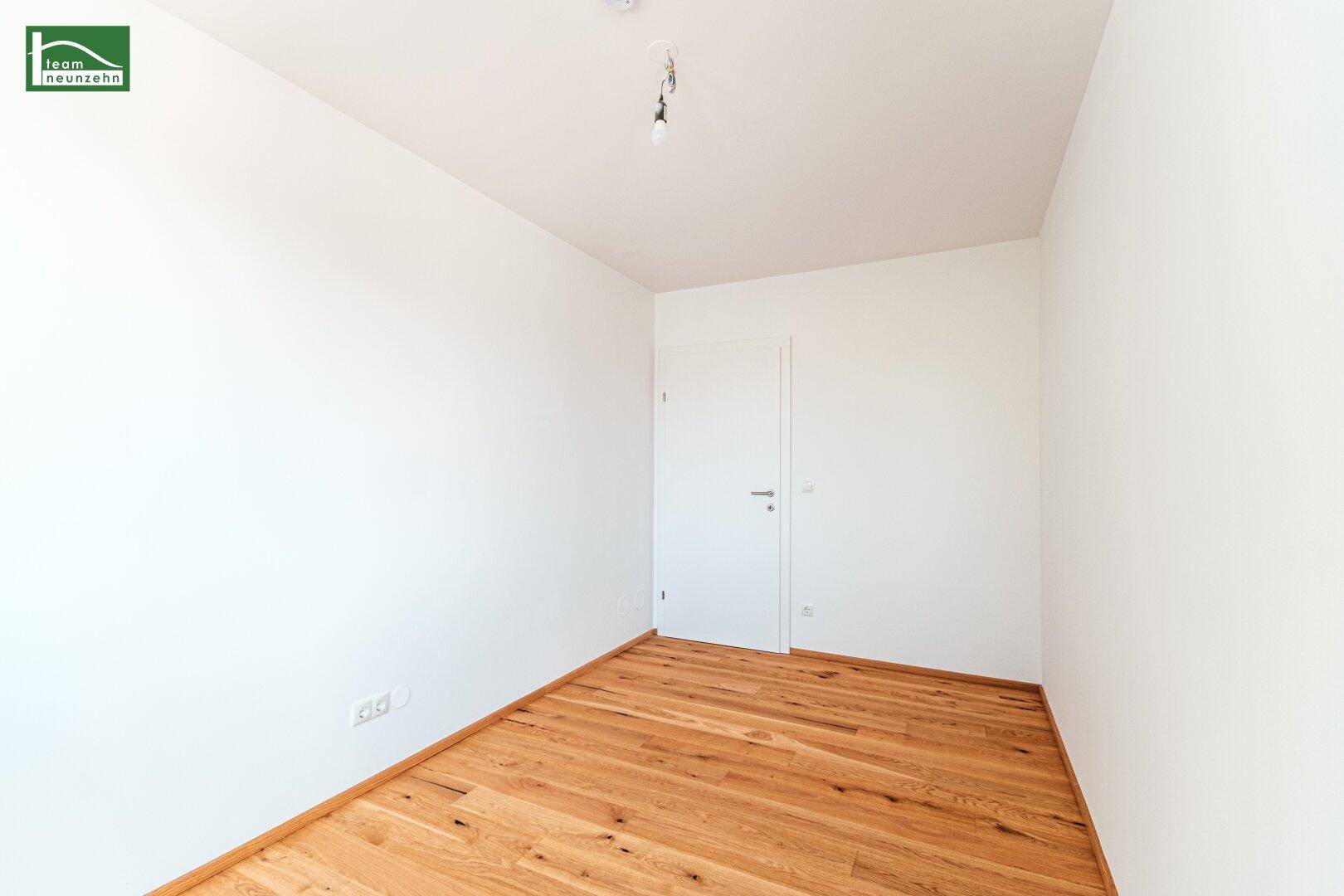 Leerer Raum mit Holzboden und einer weißen Tür, ideal für ein Schlafzimmer oder Büro.
