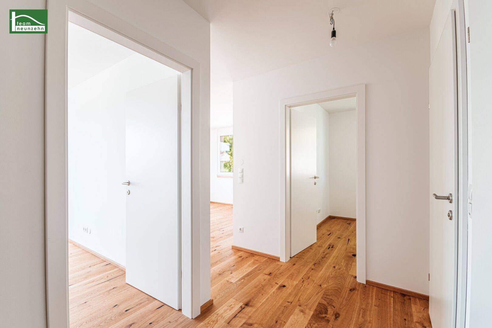 Heller Flur mit Holzboden und mehreren Türen, die zu verschiedenen Räumen führen.