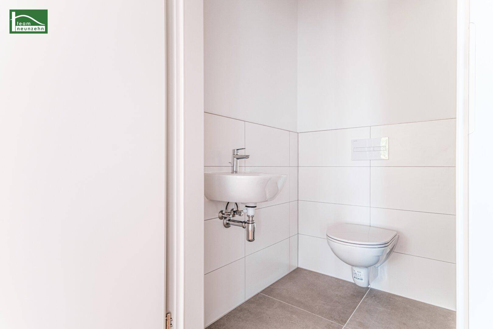 Kleines Gäste-WC mit wandhängendem WC und Waschbecken, modern gefliest und funktional.